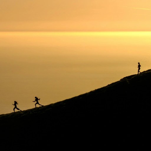 Small group of runners on a coastal hill at sunset
